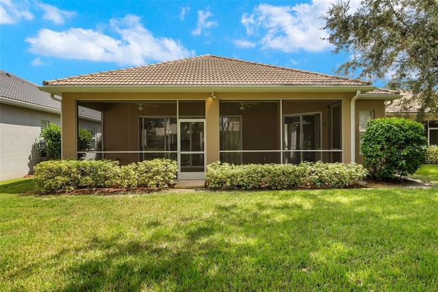 rear view of house featuring ceiling fan, a sunroom, and a lawn