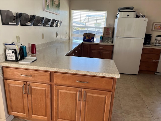 kitchen with kitchen peninsula, white fridge, and light tile patterned floors