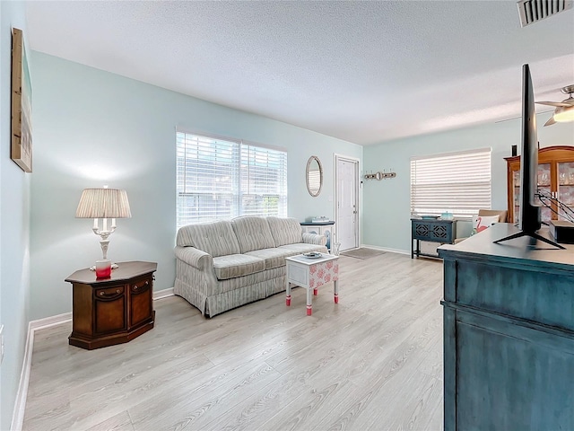 living room with ceiling fan, light hardwood / wood-style floors, sink, and a textured ceiling