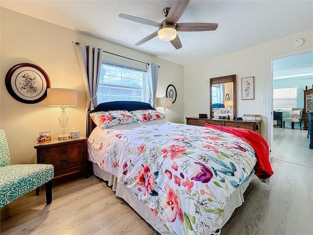 bedroom with ceiling fan, light hardwood / wood-style flooring, and multiple windows