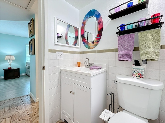 bathroom with vanity, toilet, and tile walls