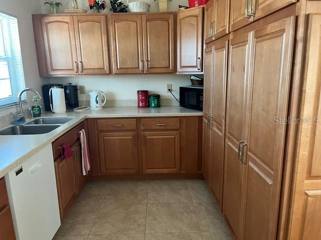 kitchen featuring sink, white dishwasher, and light tile patterned floors