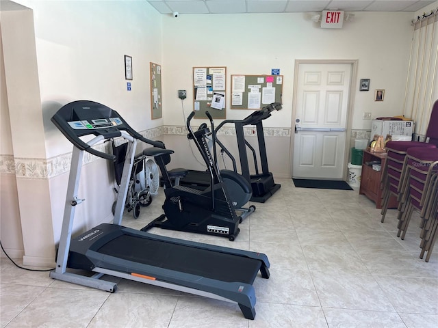 workout room featuring a paneled ceiling and light tile patterned flooring