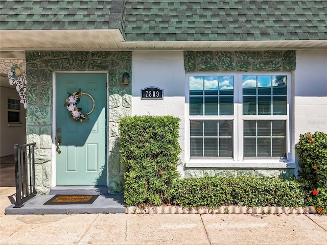 entrance to property featuring a shingled roof and mansard roof