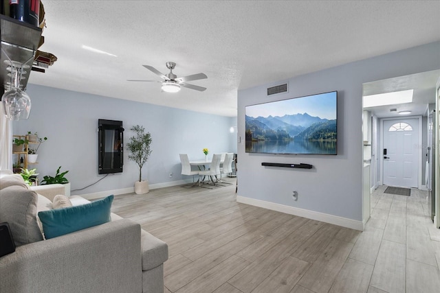 living room featuring a textured ceiling, ceiling fan, and light hardwood / wood-style floors