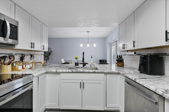 kitchen with stainless steel appliances, kitchen peninsula, sink, white cabinetry, and backsplash