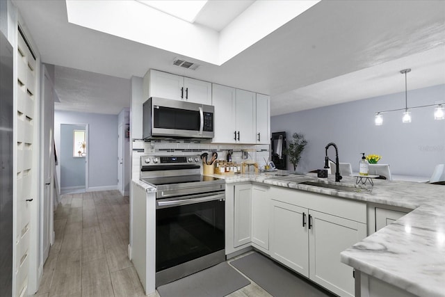 kitchen with light stone counters, stainless steel appliances, tasteful backsplash, white cabinetry, and sink