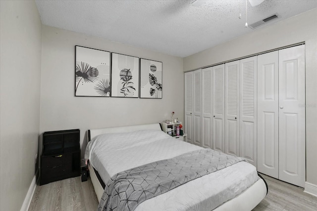 bedroom with a closet, a textured ceiling, ceiling fan, and light hardwood / wood-style flooring