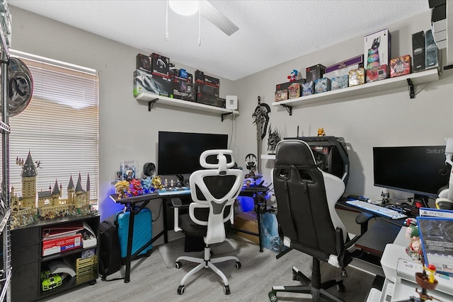 office area with a textured ceiling, ceiling fan, and light hardwood / wood-style floors