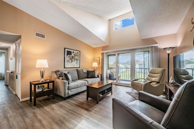 living room featuring a textured ceiling, wood-type flooring, and high vaulted ceiling