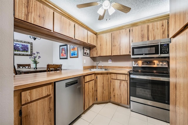 kitchen with a textured ceiling, ceiling fan, stainless steel appliances, and wooden counters