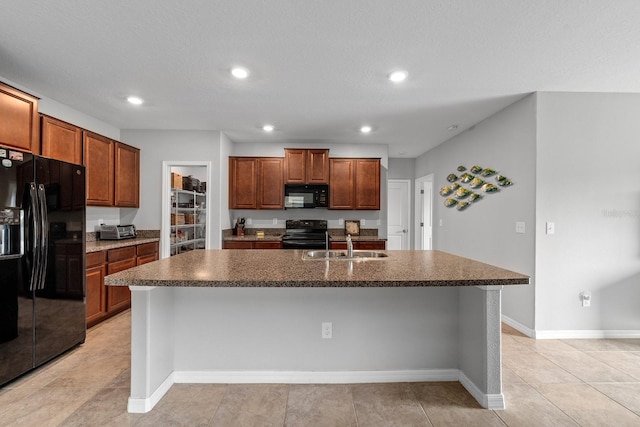 kitchen featuring light tile patterned flooring, sink, a kitchen island with sink, black appliances, and a breakfast bar