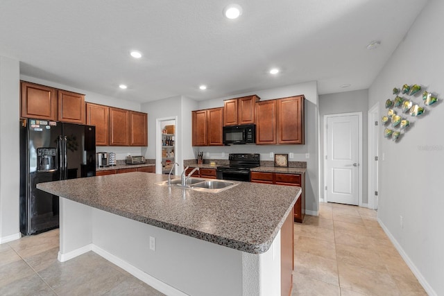 kitchen with an island with sink, light tile patterned floors, sink, black appliances, and a breakfast bar area