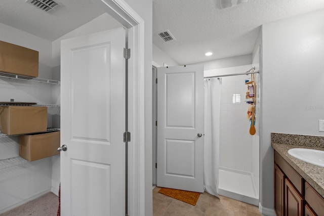 bathroom with a shower with shower curtain, tile patterned floors, a textured ceiling, and vanity