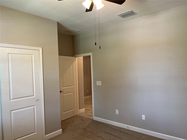 unfurnished bedroom with carpet floors, a textured ceiling, and ceiling fan