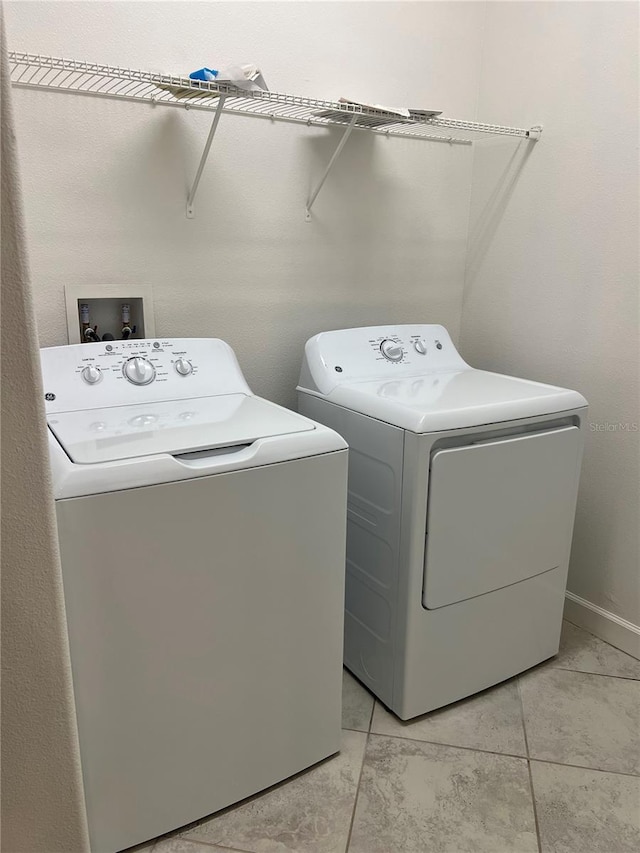 washroom with washer and clothes dryer and light tile patterned floors