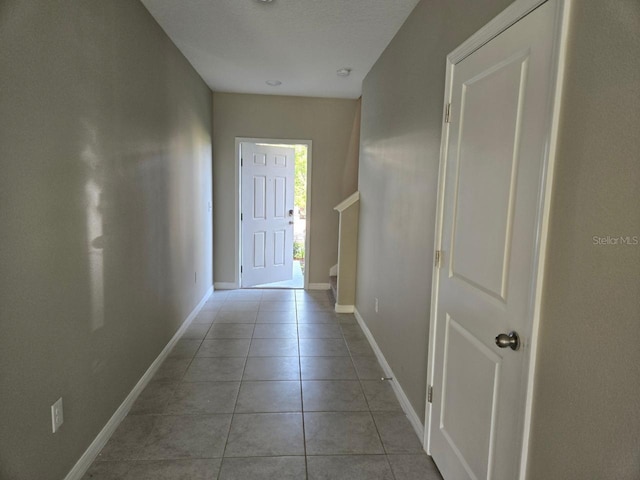 corridor with light tile patterned flooring and a textured ceiling