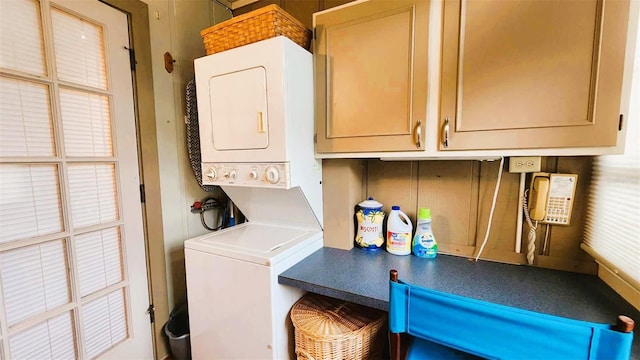 washroom featuring cabinets and stacked washer / dryer