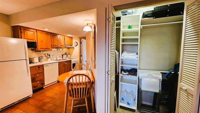 kitchen featuring a textured ceiling, white appliances, sink, and tile patterned flooring