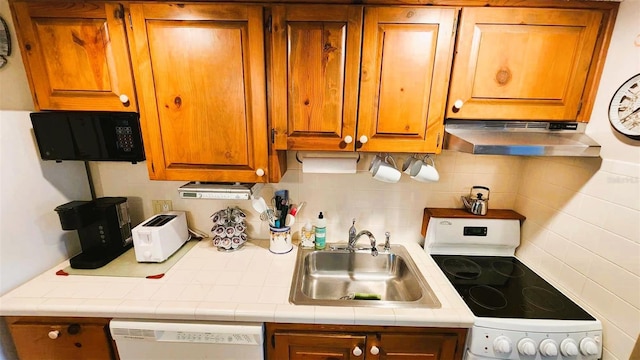 kitchen featuring white appliances, sink, and backsplash