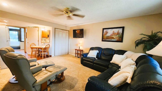 carpeted living room featuring ceiling fan and a textured ceiling