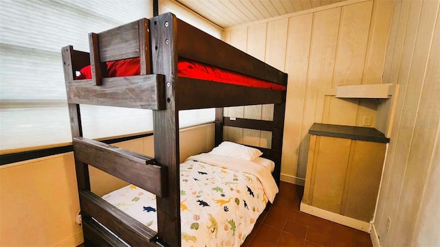 bedroom featuring wooden walls and dark tile patterned flooring