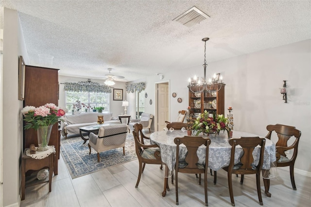 dining space with light hardwood / wood-style floors, a textured ceiling, and ceiling fan with notable chandelier