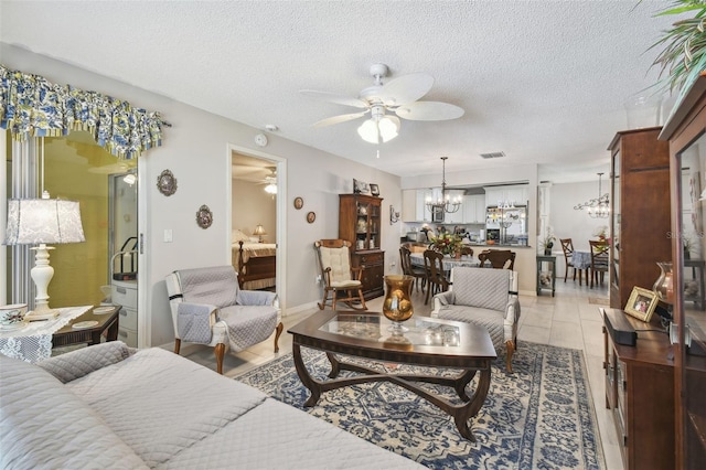 tiled living room with a textured ceiling and ceiling fan with notable chandelier