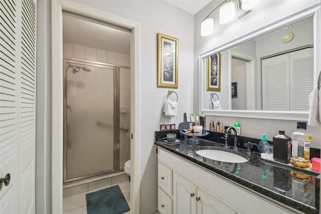 bathroom featuring vanity, toilet, tile patterned floors, and an enclosed shower