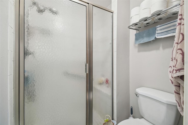 bathroom featuring toilet and a shower with door