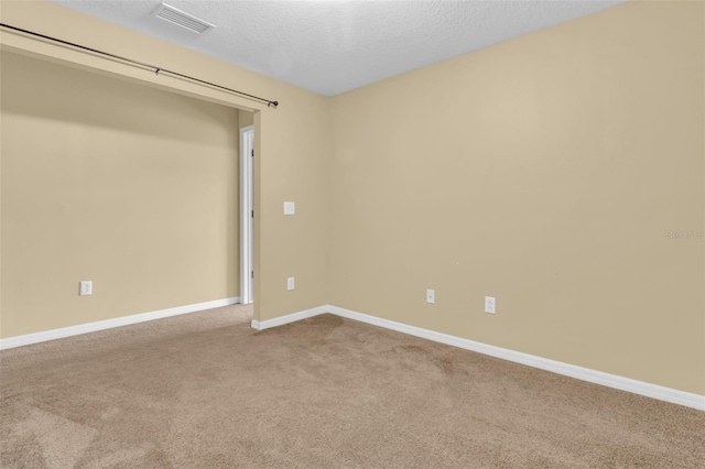 carpeted empty room with a textured ceiling