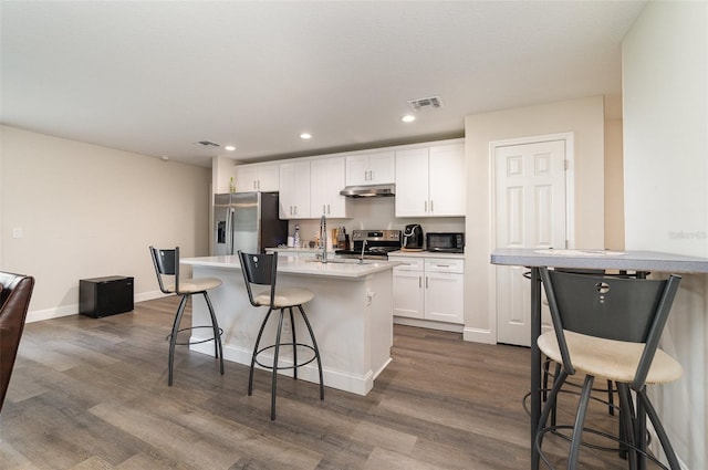 kitchen with a kitchen breakfast bar, a kitchen island with sink, appliances with stainless steel finishes, and white cabinets