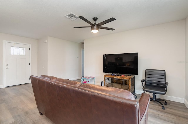 living room with ceiling fan, a textured ceiling, and light wood-type flooring