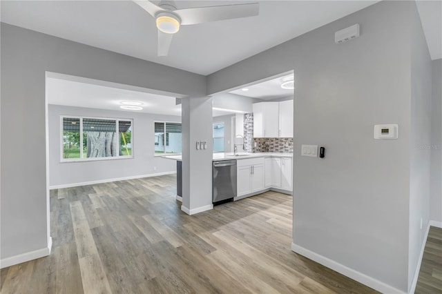 kitchen featuring sink, dishwasher, white cabinetry, backsplash, and light hardwood / wood-style floors