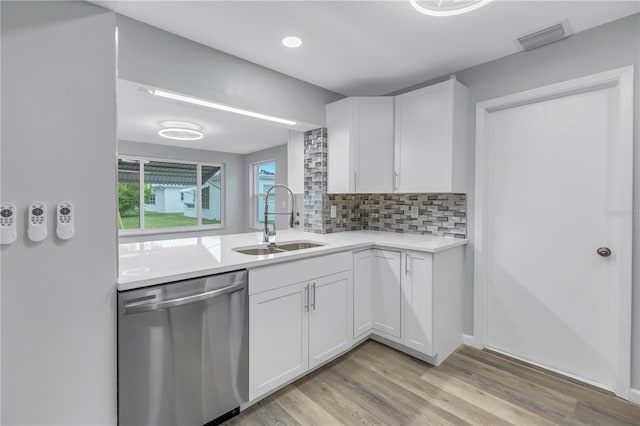 kitchen with white cabinetry, stainless steel dishwasher, sink, and tasteful backsplash