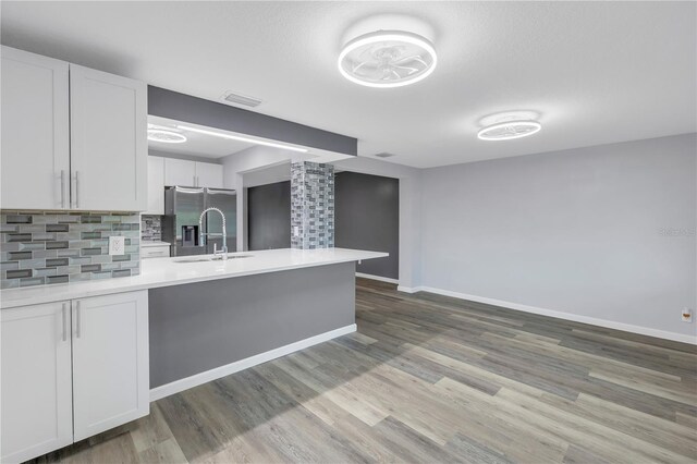 kitchen with sink, white cabinetry, hardwood / wood-style floors, stainless steel refrigerator with ice dispenser, and decorative backsplash