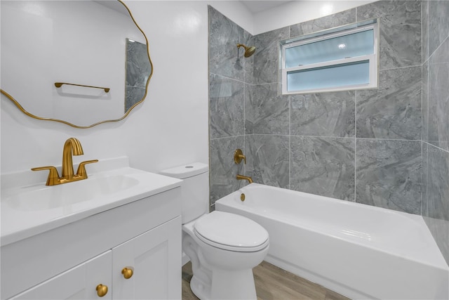 full bathroom featuring vanity, hardwood / wood-style floors, tiled shower / bath combo, and toilet