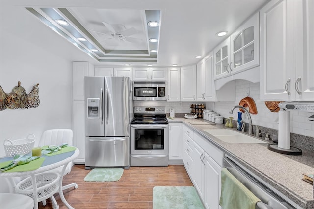 kitchen with white cabinets, light hardwood / wood-style floors, appliances with stainless steel finishes, and sink