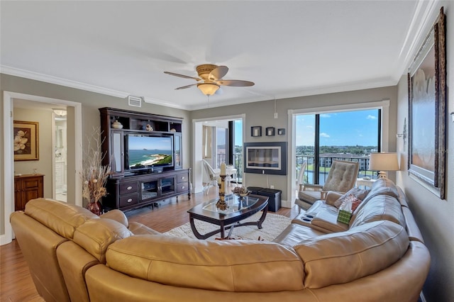 living room featuring ceiling fan, crown molding, and light hardwood / wood-style floors