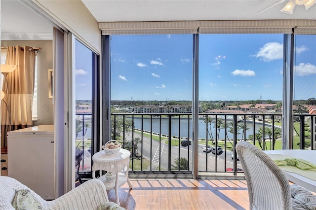 sunroom featuring a water view, ceiling fan, and plenty of natural light