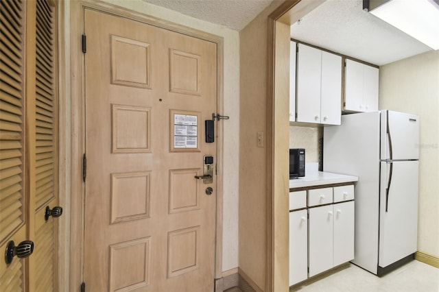 kitchen with white cabinets, white refrigerator, and a textured ceiling