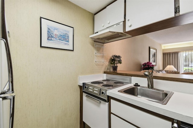 kitchen with electric stove, sink, and white cabinets