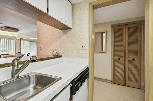 kitchen featuring sink, a textured ceiling, white cabinetry, dishwasher, and light carpet