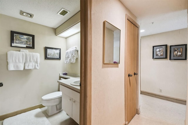 bathroom with a textured ceiling, vanity, and toilet