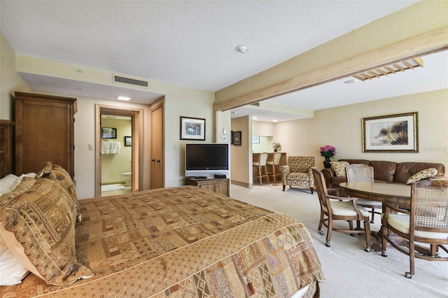 bedroom featuring light colored carpet, a textured ceiling, and ensuite bath