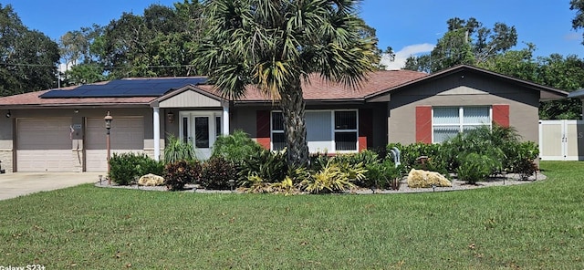 ranch-style home featuring a garage, solar panels, and a front lawn