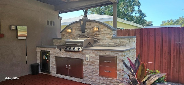 view of patio with grilling area, a deck, and exterior kitchen