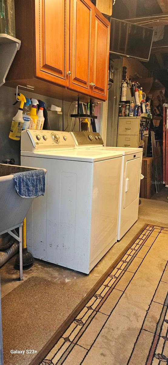 clothes washing area with cabinets and separate washer and dryer