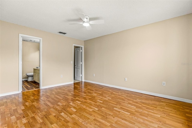 unfurnished bedroom featuring light hardwood / wood-style floors, ceiling fan, connected bathroom, and a textured ceiling