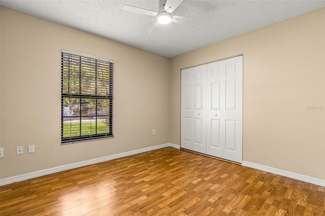 unfurnished bedroom with a textured ceiling, ceiling fan, light hardwood / wood-style floors, and a closet